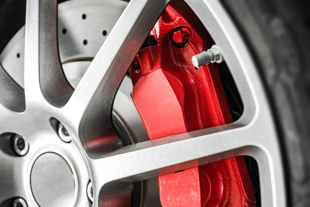 Red brake caliper behind an alloy wheel